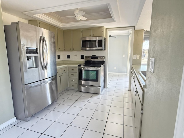 kitchen featuring light tile patterned floors, ceiling fan, a tray ceiling, stainless steel appliances, and crown molding