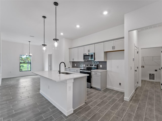 1818 New London St, North Port, FL 34288 - kitchen with stainless steel appliances, light countertops, backsplash, wood finished floors, and a kitchen island with sink