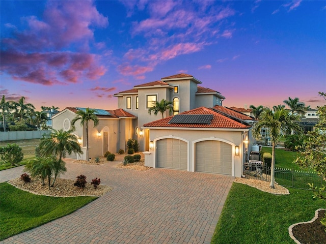 mediterranean / spanish home with a yard, a garage, and solar panels