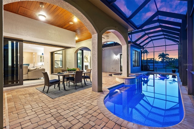 pool at dusk featuring a lanai and a patio area