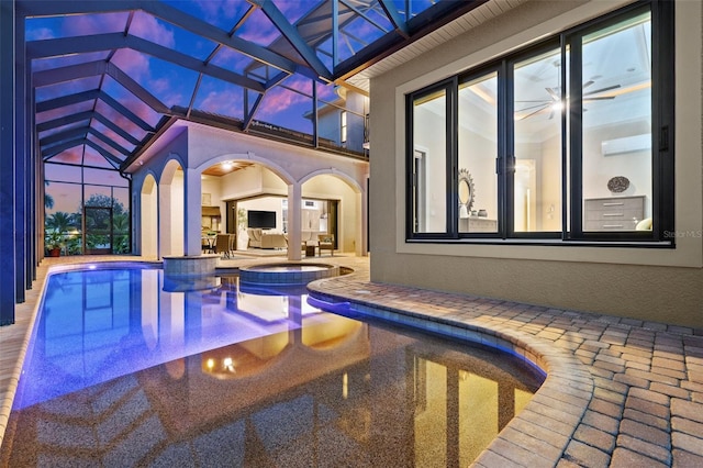 pool at dusk featuring an in ground hot tub, a lanai, and a patio