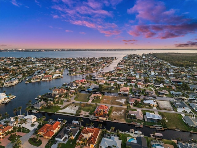 aerial view at dusk featuring a water view