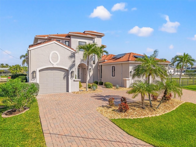 mediterranean / spanish-style house featuring a garage, a front lawn, and solar panels