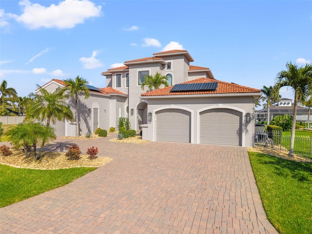 mediterranean / spanish-style house featuring a garage, a front lawn, and solar panels