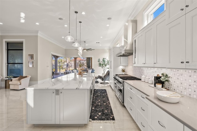 kitchen featuring a large island, white cabinetry, decorative light fixtures, wall chimney exhaust hood, and range with two ovens