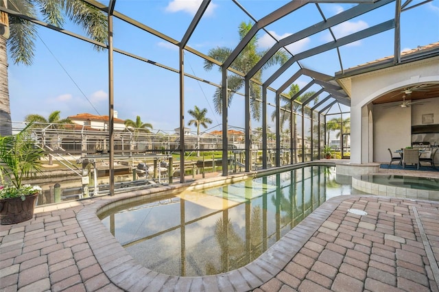 view of pool with ceiling fan, a water view, glass enclosure, and a patio area