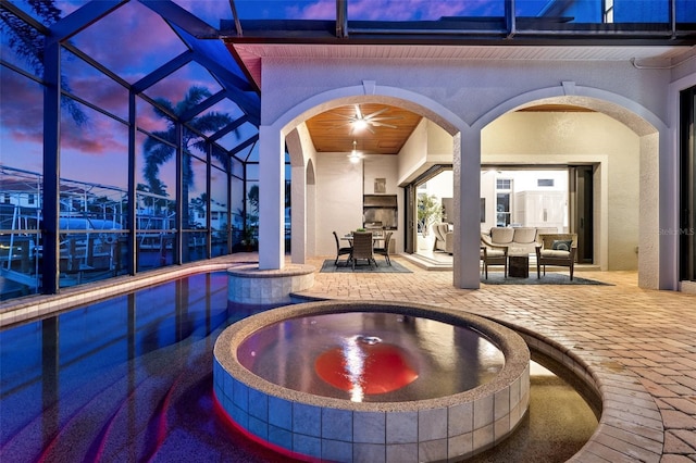 pool at dusk featuring an in ground hot tub