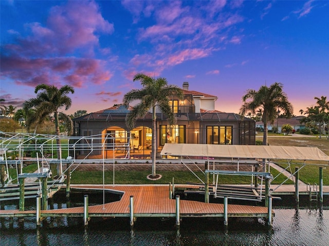 back house at dusk with a water view and a lanai