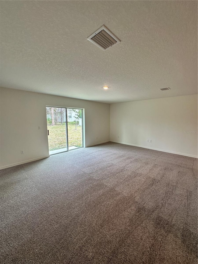 carpeted spare room featuring visible vents, a textured ceiling, and baseboards