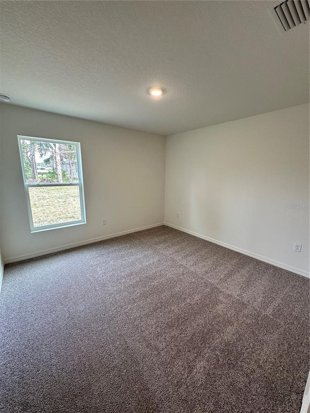 empty room with baseboards, carpet, visible vents, and a textured ceiling