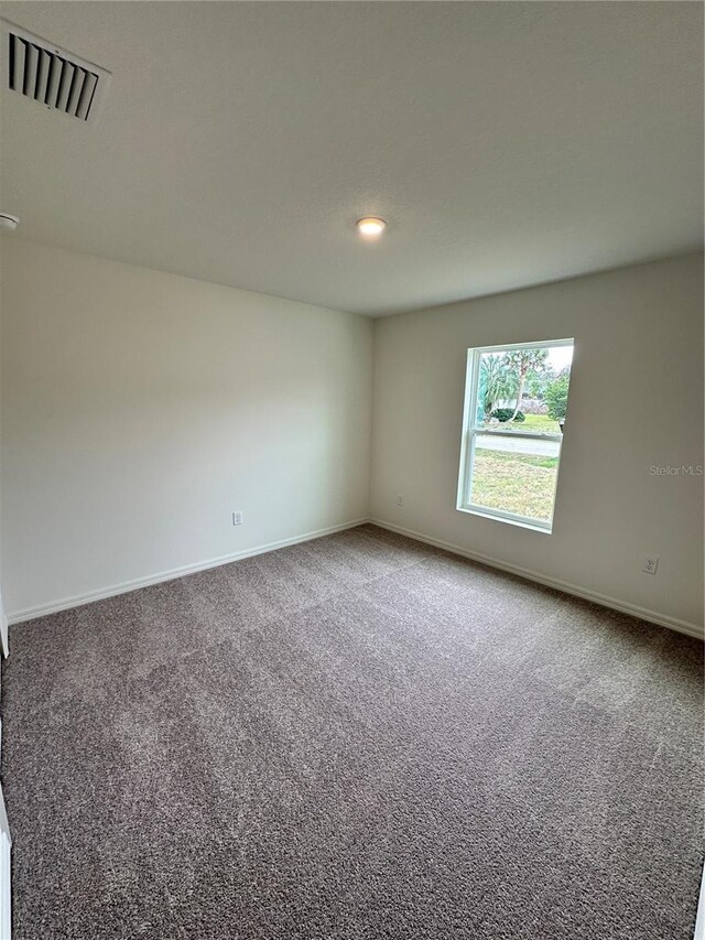 carpeted spare room with baseboards and visible vents