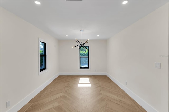 spare room featuring an inviting chandelier, plenty of natural light, and light parquet floors