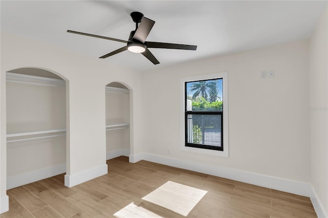 unfurnished bedroom with light hardwood / wood-style flooring, ceiling fan, and two closets