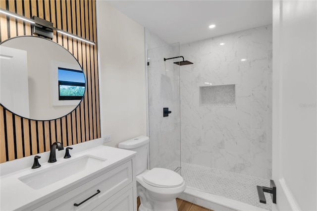 bathroom featuring toilet, vanity, and tiled shower