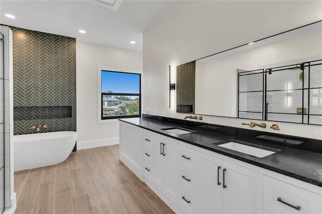bathroom with tile walls, vanity, and a tub to relax in