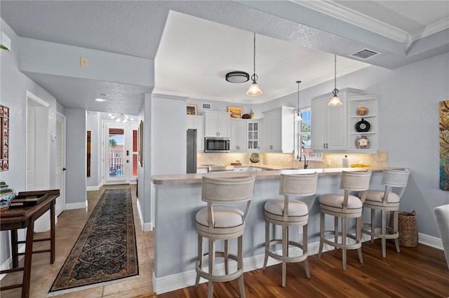 kitchen with sink, a breakfast bar area, white cabinetry, tasteful backsplash, and kitchen peninsula