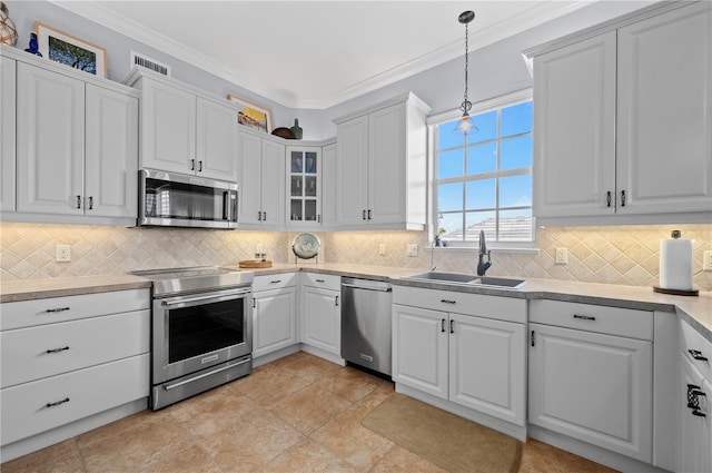 kitchen with appliances with stainless steel finishes, pendant lighting, sink, white cabinets, and crown molding