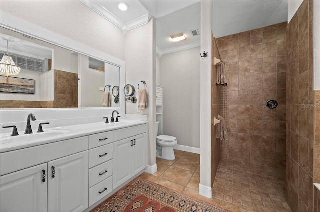 bathroom with tile patterned flooring, vanity, tiled shower, toilet, and crown molding