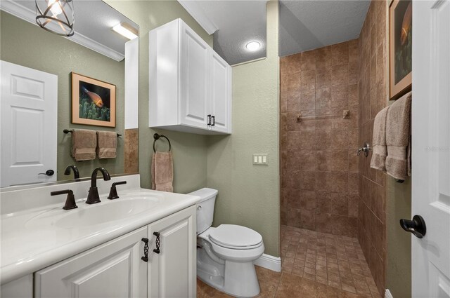 bathroom featuring tile patterned flooring, vanity, a tile shower, and toilet