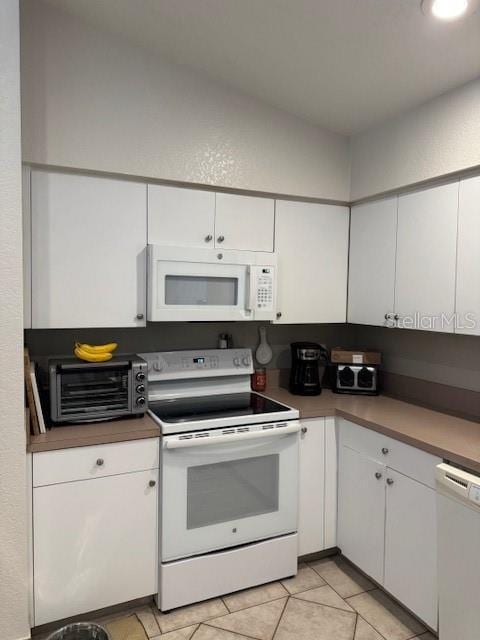 kitchen with white appliances, a toaster, white cabinets, and light tile patterned flooring