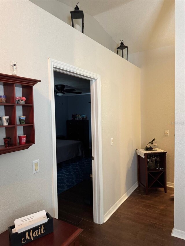 corridor featuring vaulted ceiling, dark wood finished floors, and baseboards