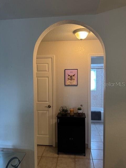 hallway with light tile patterned floors and arched walkways