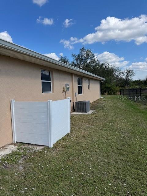 view of property exterior featuring a yard, central air condition unit, and stucco siding