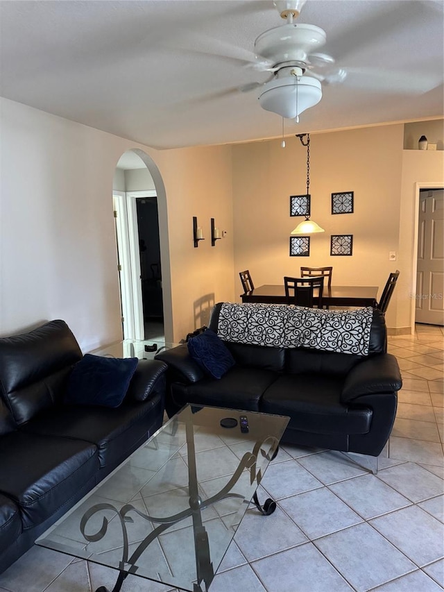 living room with light tile patterned floors, arched walkways, and a ceiling fan