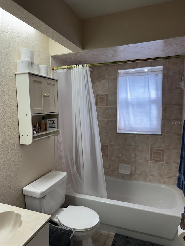 full bathroom featuring a textured wall, shower / tub combo with curtain, vanity, and toilet