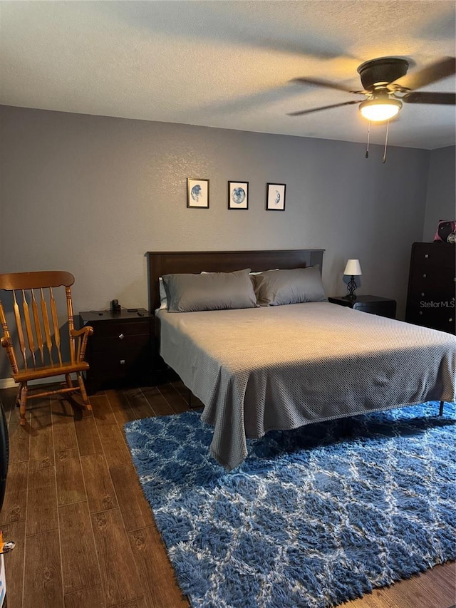 bedroom with dark wood-style floors, ceiling fan, and a textured ceiling