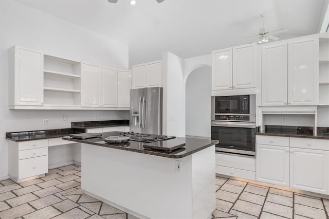 kitchen with a breakfast bar area, ceiling fan, appliances with stainless steel finishes, white cabinetry, and a kitchen island