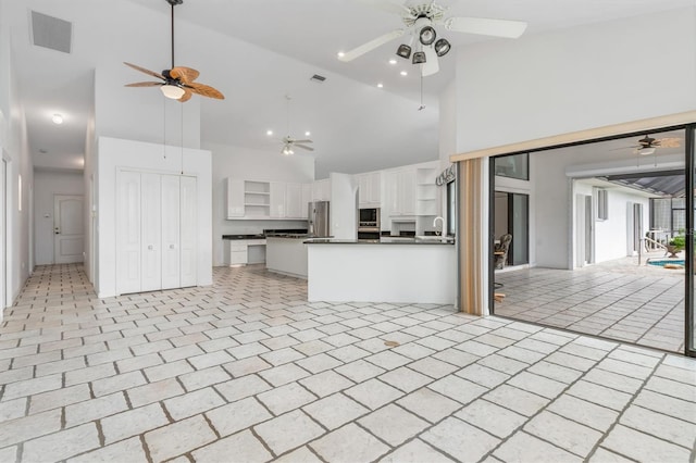 kitchen featuring built in microwave, sink, stainless steel fridge, ceiling fan, and white cabinets