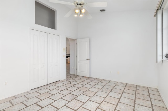 unfurnished bedroom featuring a towering ceiling, ceiling fan, and a closet