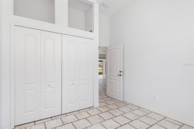 unfurnished bedroom featuring a towering ceiling and a closet