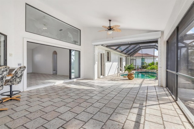 view of patio featuring ceiling fan and glass enclosure