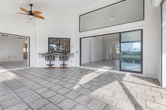 unfurnished living room with ceiling fan and a high ceiling