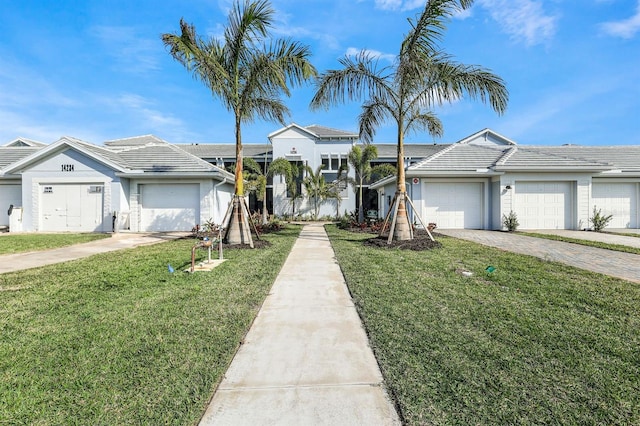 view of front of property with a tiled roof, a garage, decorative driveway, and a front yard