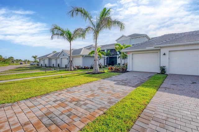 ranch-style home featuring stucco siding, an attached garage, decorative driveway, a tile roof, and a front yard