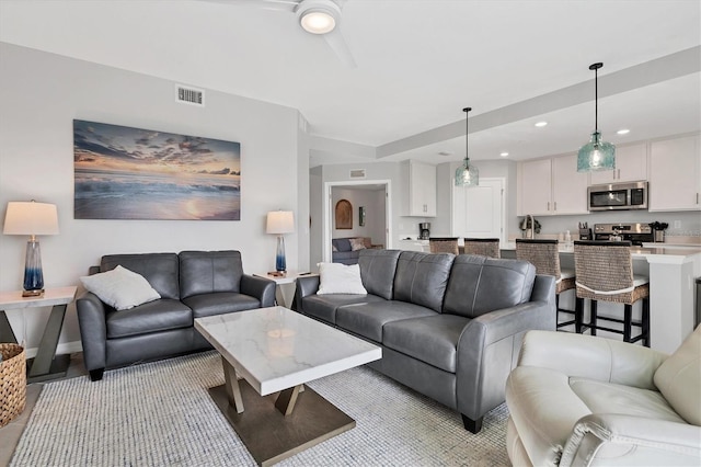 living area with baseboards, a ceiling fan, visible vents, and recessed lighting