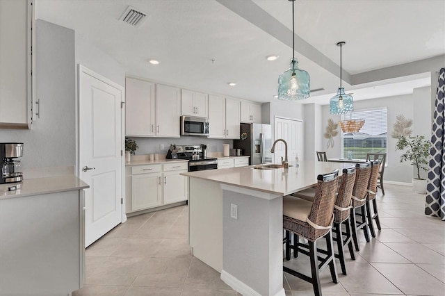 kitchen with visible vents, hanging light fixtures, white cabinetry, light countertops, and stainless steel appliances