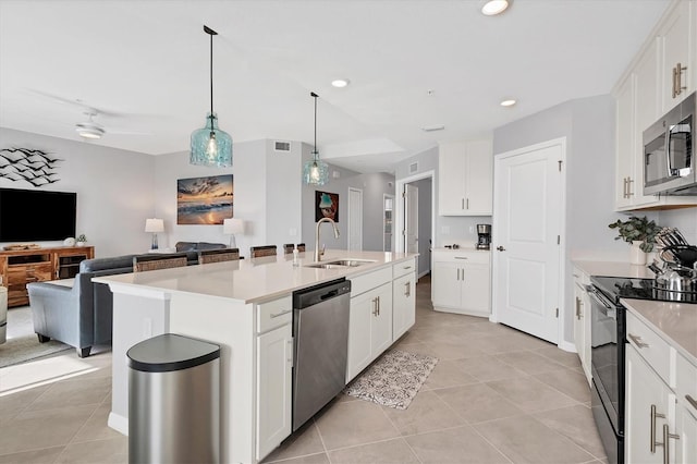 kitchen featuring a center island with sink, light countertops, stainless steel appliances, open floor plan, and white cabinetry