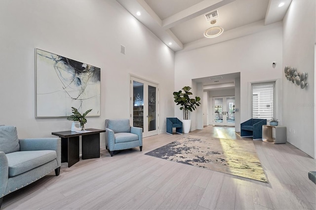 foyer with visible vents, light wood-style floors, beam ceiling, and french doors