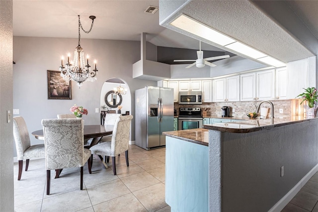 kitchen featuring white cabinetry, stainless steel appliances, decorative backsplash, ceiling fan with notable chandelier, and kitchen peninsula