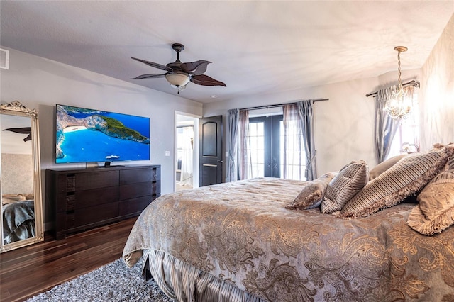 bedroom with dark hardwood / wood-style floors, ceiling fan with notable chandelier, and french doors