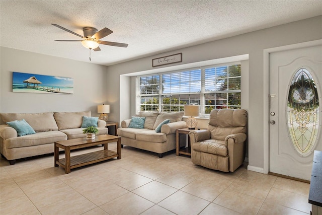 living room featuring light tile patterned floors, a textured ceiling, baseboards, and a ceiling fan