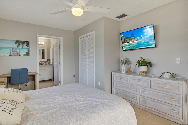 bedroom featuring light tile patterned floors, visible vents, ensuite bath, ceiling fan, and a closet