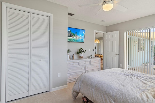 bedroom featuring light tile patterned floors, visible vents, ceiling fan, a textured ceiling, and a closet