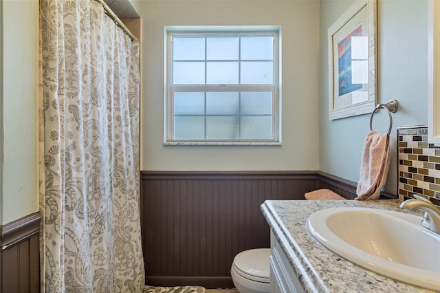 full bath featuring toilet, a wainscoted wall, and vanity