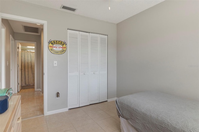 bedroom featuring light tile patterned floors, visible vents, and a closet