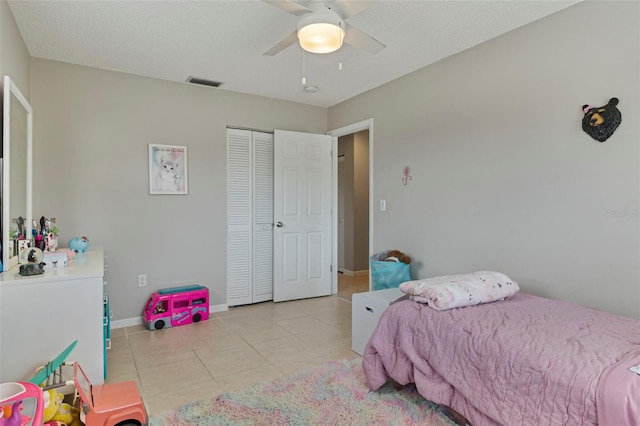 bedroom with light tile patterned floors, a ceiling fan, visible vents, baseboards, and a closet